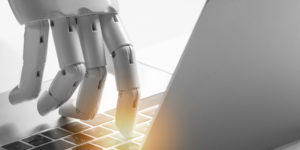 A robot presses a key on a laptop keyboard