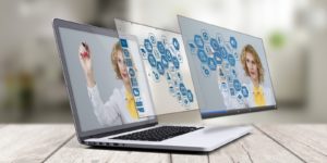 A laptop sits open with two identical screens overlapping the original screen.