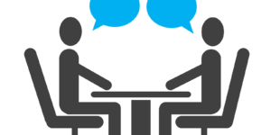 Two people sitting across a desk from each other with blue speech bubbles