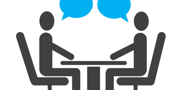Two people sitting across a desk from each other with blue speech bubbles