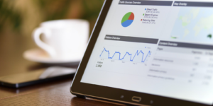 Tablet screen showing different graphs next to a coffee cup.