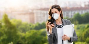 A women wearing a mask holding a folder and checking here cell phone