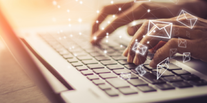 A person typing on a keyboard with a web if envelopes around them