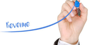 Person writing the word revenue with blue marker to show increased sales