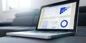A laptop sitting on a sofa showing various charts and graphs.