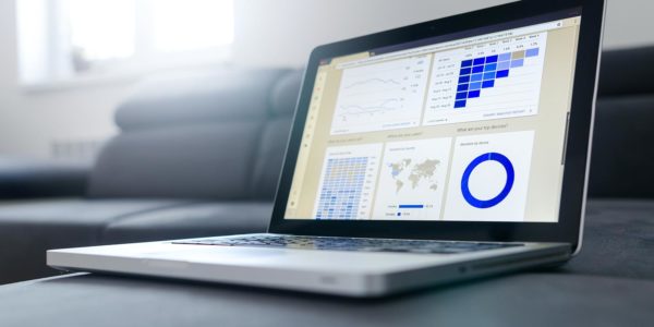 A laptop sitting on a sofa showing various charts and graphs.