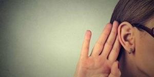 A woman holding her hand up to her ear