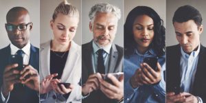 A group of people in dress clothes texting on their smartphones.