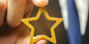 A person's hand holding a gold star.
