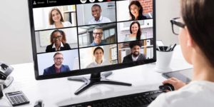 A person sitting in front of a computer monitor taking part in a virtual meetin