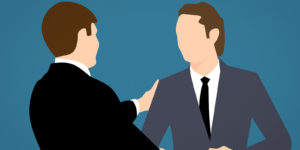 Two men in suits shaking hands.