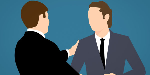 Two men in suits shaking hands.