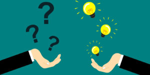 An image of two hands, one holding a number of question marks, and the other holding light bulbs.