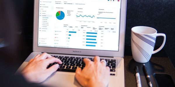 A person sitting in front of a laptop looking at different graphs and charts.