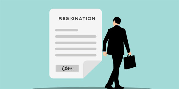 A person in a suit and tie holding a briefcase standing in front of a resignation letter.