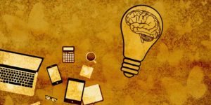A brain inside a lightbulb next to a laptop, smart phone, and a tablet.