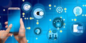A person holding a smart phone with different icons floating around the phone.