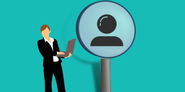 A person in business clothes holding a laptop standing in front of an icon of a person
