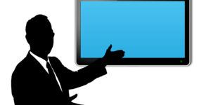 A person presenting in front of a large blue screen.