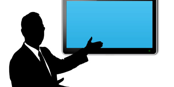A person presenting in front of a large blue screen.
