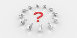 A group of people sitting around a large red question mark.