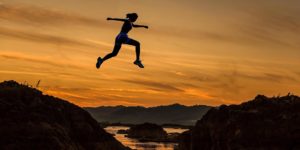 A women jumping across a small river will running