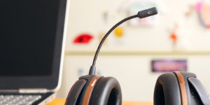 A black and brown headset placed next to a laptop with a black screen and a blurry background.