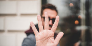 Blurry background image of a man holding up his outstretched hand in the foreground