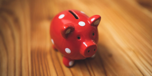 A pink and white polka dotted piggy bank on a wooden table