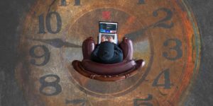 A person sits in a chair on a laptop atop a floor made out of a clock