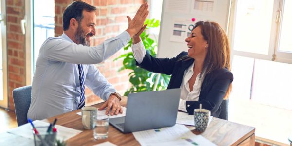 A man and a woman smile while they high five at work