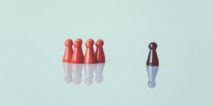 A group of game pieces sit on a white surface with one piece standing alone