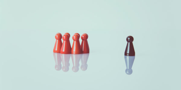 A group of game pieces sit on a white surface with one piece standing alone