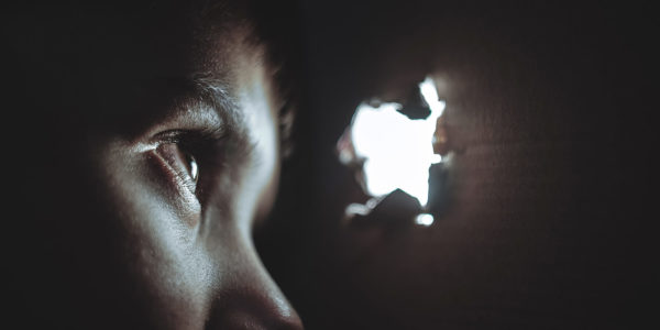 A child looks through a hole in a cardboard box, in black and white.