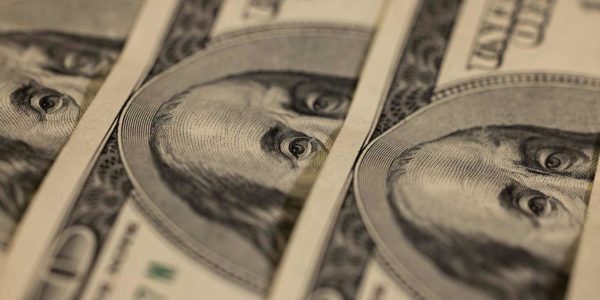 Three one-hundred dollar bills are stacked one on top of the other.
