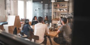 Seven people happily sit around a table at lunch and listen to one person talk