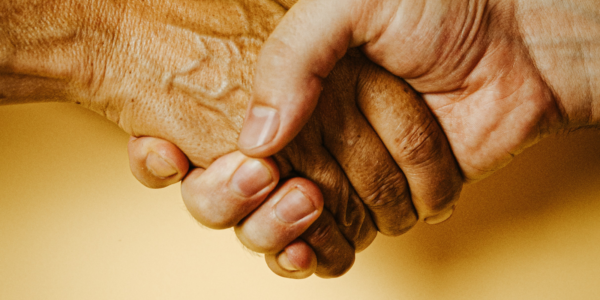 Two hands hand shake against a yellow background.