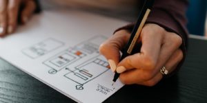 A person draws a plan on a piece of paper with a pen.