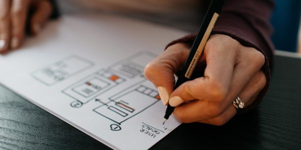 A person draws a plan on a piece of paper with a pen.
