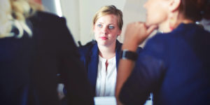 A woman listens as two other women talk to each other