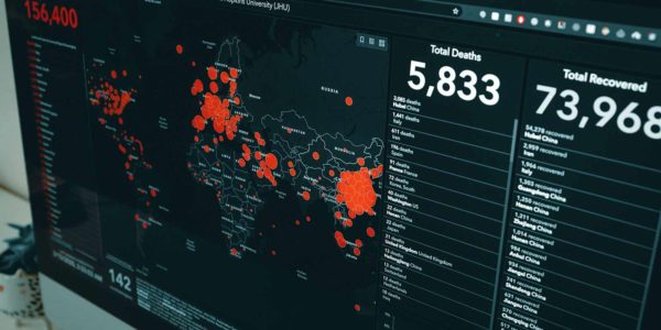A computer screen shows red dots of coverage of the entire world with numbers in the thousands in the upper right corner.