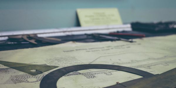 A blueprint is laid out on a table with a protractor on top of it.