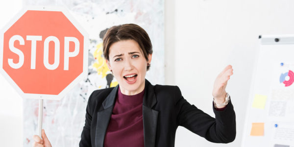 A smiling woman holds up a stop sign.