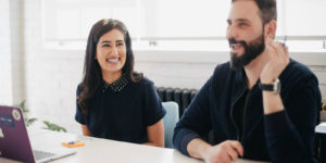 Two people sit at a table smiling.