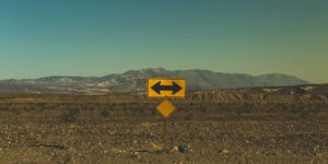 A road sign points in both directions with mountains in the background.