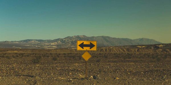 A road sign points in both directions with mountains in the background.