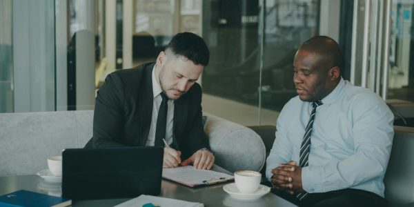 Two business men signing a document at a table.