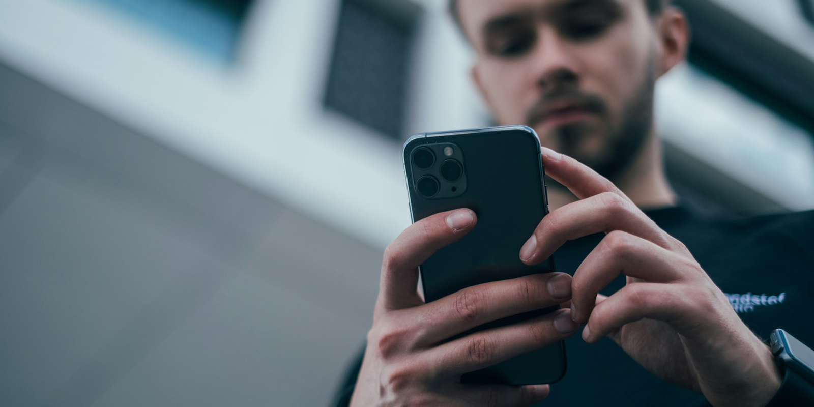 Men wearing black sweater checking his phone.