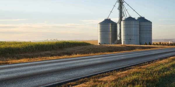 A group of silver silos along a highway.