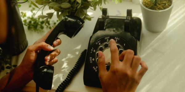 Person holding black rotary telephone 